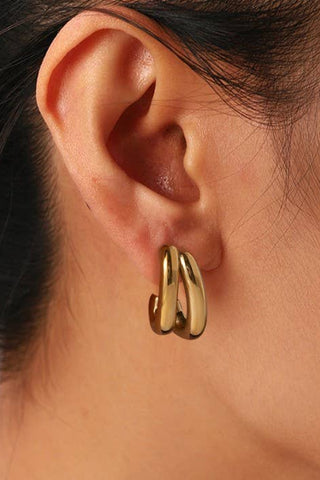 Close-up of an ear wearing a gold hoop earring with hair partially visible.