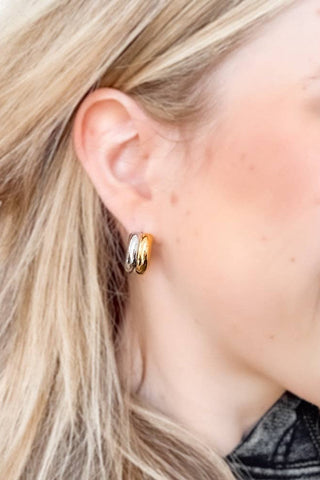 Close-up of a woman wearing gold hoop earrings with a blurred background