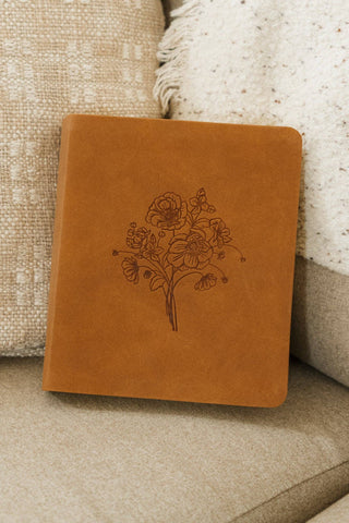 Brown leather notebook with floral design on a beige couch