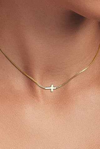 Gold necklace with a small cross pendant on a person's neck