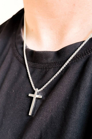 Silver cross necklace on a person wearing a black shirt