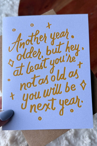 Hand holding a card with gold text on a textured surface