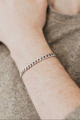 Person wearing a silver bracelet on a neutral background