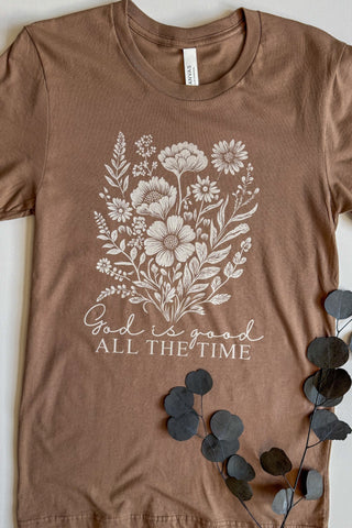 Brown t-shirt with floral design and 'God is good all the time' text on a white background