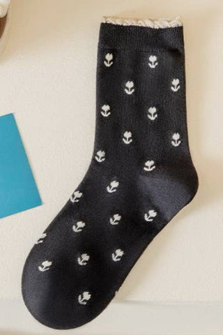 Black sock with white floral patterns on a light background